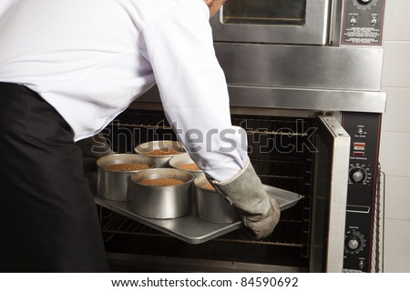 Cook placing the cakes in the oven