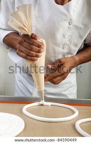 Cook making meringue rings with a piping bag