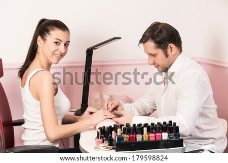 Man manicurist doing manicure for woman in beauty salon