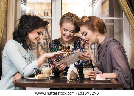 Three women friends in cafe looking at tablet