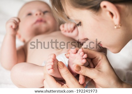 mother kissing baby\'s feet. Close up image.