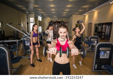 fitness, sport, training, gym and lifestyle concept - smiling trainer in front of the group of people working out with barbells in the gym