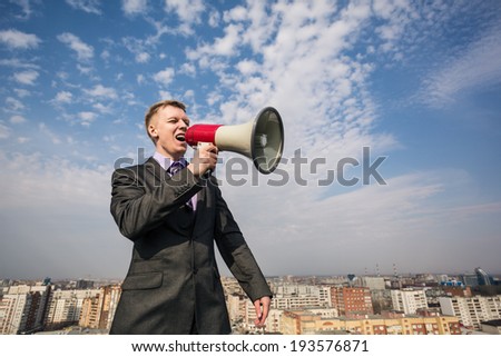 young businessman in suit screaming into megaphone on the roof