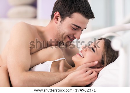Beautiful young loving couple lying in bed