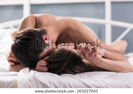 young lovers kissing on the bed focused on hand