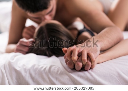 young lovers kissing on the bed focused on hand
