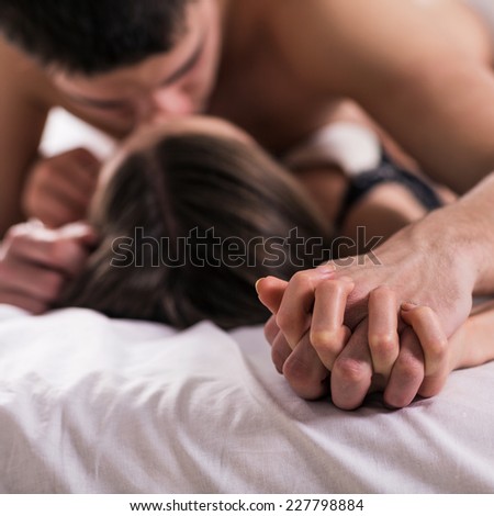 Young passionate couple making love in bed.  Focused on hand
