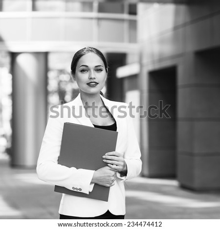 Happy young business woman with a folder at the office building