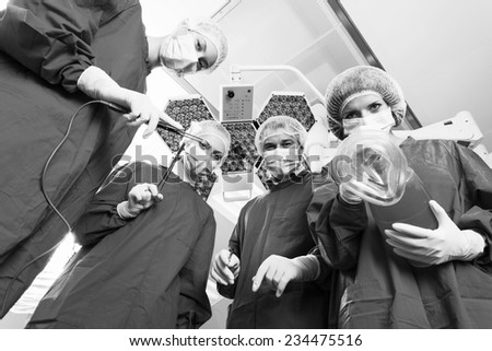 Below view of surgeons holding medical instruments in hands and looking at patient