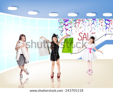 Little fashion girls with packages in a large shopping center. Pretty smiling little girls with shopping bags posing in the shop