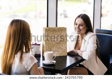 Happy women with coffee cup while keeping company in cafe