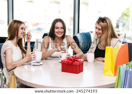 Happy women with coffee cup while keeping company in cafe