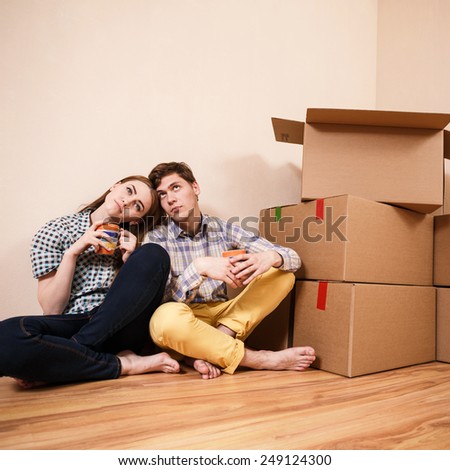Young Couple with boxes of drinking coffee in the new apartment