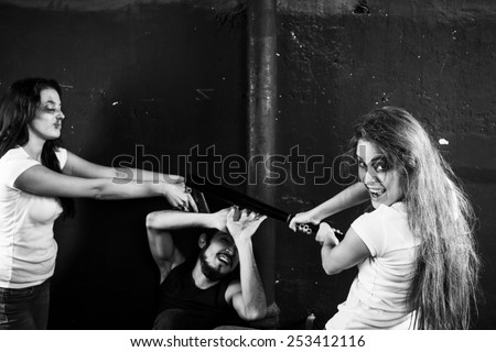 Two young women beating and shooting man on black-and-white background