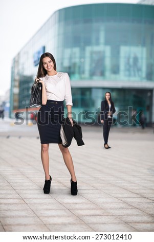 Full length portrait of a business woman walking with briefcase near office building