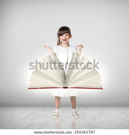 Happy cute little girl and big book in front of she