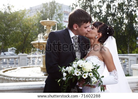 Bride and groom kissing with the fountain on the background