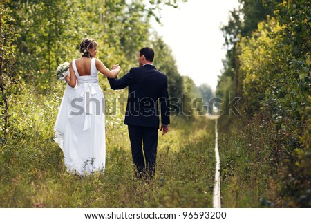 Newlyweds walks away outdoors. Railroad in the forest