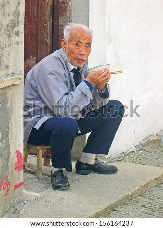 LUZHI, SHANGHAI, CHINA -Â?Â? OCTOBER 30: old man having supper at his house door. The ancient village is a Shanghai tourist attraction with 100000 visitors per year. October 30, 2004 Luzhi, China.