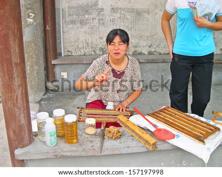 FENGJING, SHANGHAI, CHINA - SEPTEMBER 19: girl selling honey on the street. The ancient village is a Shanghai tourist attraction with 100000 visitors per year. September 19, 2004, Fengjing, China