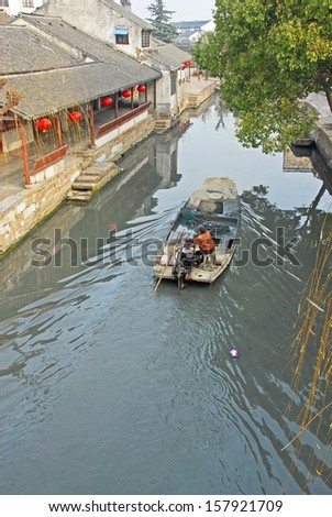 JINXI, SHANGHAI, CHINA  JANUARY 9: man run a boat in a typical village water way.  The ancient village is a Shanghai tourist attraction with 100000 visitors per year. January 9, 2010, Jinxi, China