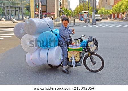SHANGHAI, CHINA-AUGUST 24, 2013: guy running a motorcycle transport. The largest Chinese city by population has thousand of these transports.