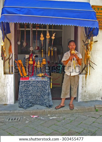ZHUJIAJIAO, SHANGHAI-AUGUST 8, 2004: guy selling typical Chinese music instruments. Zhujiajiao ancient village is a Shanghai tourist attraction with more than 1000000 visitors per year.