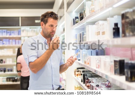Elegant man choosing perfume in retail store. Casual man testing and buying gift for his lady in a beauty store.