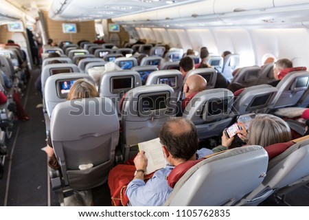 Interior of large commercial airplane with unrecognizable passengers on their seats during flight.