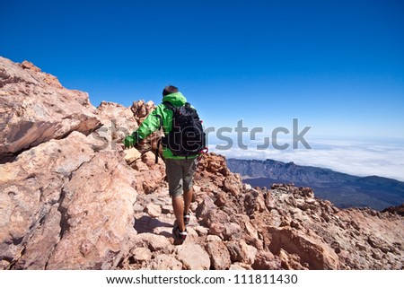 Man hiking. Young  guy hiking / backpacking in the rough  volcanic landscape on the volcano, Teide, highest peak of Spain.