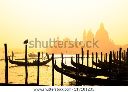 Romantic Italian city of Venice Venezia a World Heritage Site traditional Venetian wooden boats gondolier and Roman Catholic church Basilica di Santa Maria della Salute in the misty background Romantic Italian city of Venice Venezia a World Heritage Site traditional Venetian wooden boats gondolier and Roman Catholic church Basilica di Santa Maria della Salute in the misty background