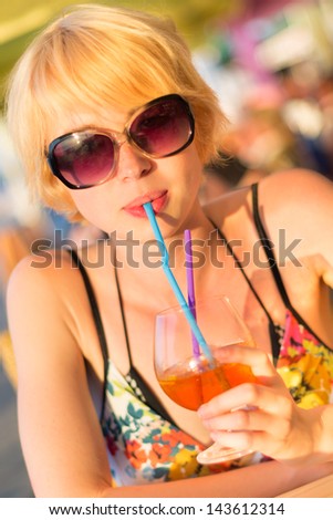 Cute young lady  drinking cocktail on the outdoor terrace on a lovely sunny  day.