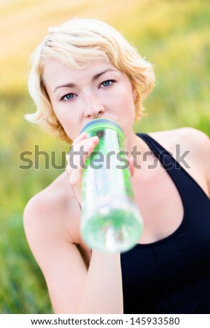 Lady drinking from the bottle during outdoor activities.