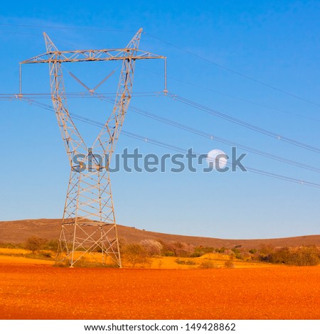 High tension  transmission lines crossing the colorful fields with moon in the sky.