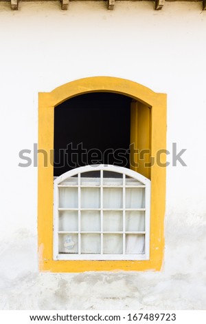 Decorative, colonial, yellow, vintage, window on a white wall in Paraty (or Parati), Brazil.