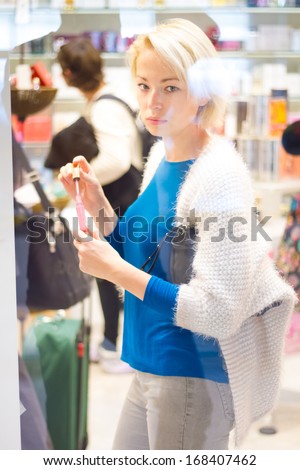 Casual blond young woman buying nail polish in supermarket.