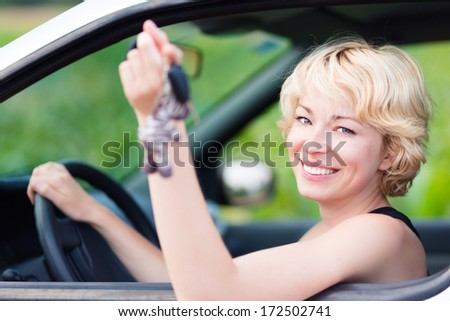 Woman, driving showing car keys out the window. Young female driving happy about her new car or drivers license. Caucasian model.