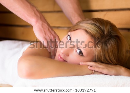 Young beautiful lady relaxing with massage treatment in traditional wooden Finnish sauna.