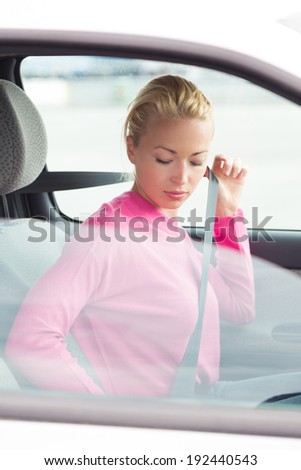 Beautiful lady fastening car seat belt.