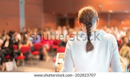 Female academic professor lecturing at Conference. Audience at the lecture hall.