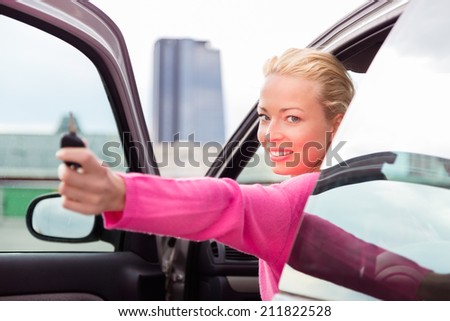 Woman driver showing car keys. Young female driving happy about her new car or drivers license. Caucasian model.