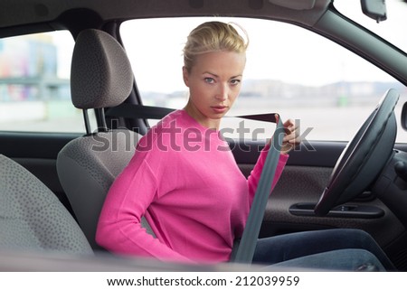 Safety first. Beautiful blonde caucasian lady fastening car seat belt.