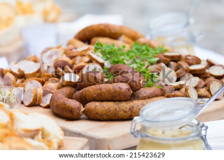 Dry sausage cold cuts. A variety of dry cold smoked meat products with herbs and mustard and  horseradish spreadon a wooden cutting board.