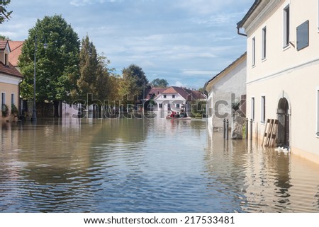 Rural village houses in floodwater. Road with the river overflown with the residents in their homes. Floods and flooding the streets. Natural disaster.