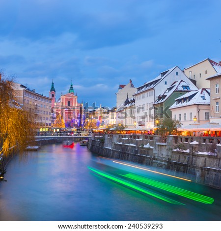 View of lively river Ljubljanica bank and Tromostovje in old city center decorated with Christmas lights at dusk. Ljubljana, Slovenia, Europe.
