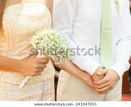 Close up of a bride and groom holding hands during wedding ceremony.