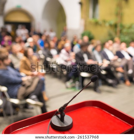 Microphone on a Podium Desk at Business Event. Audience at the conference hall. Business and Entrepreneurship. Business woman. Focus on microphone.