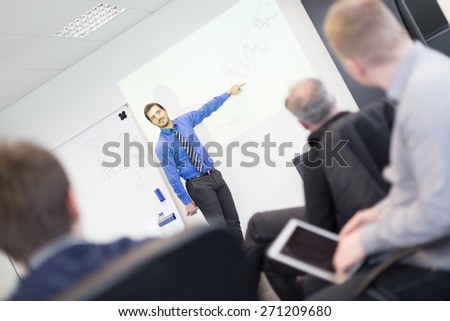 Business man making a presentation at office. Business executive delivering a presentation to his colleagues during meeting or in-house business training, explaining business plans to his employees.