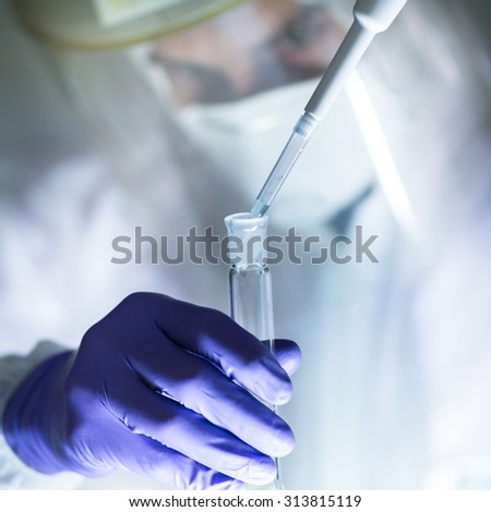Life scientist researching in laboratory. Focused life science professional pipetting human serum media containing HIV infected cells. High protection degree work. Health care and biotechnology.