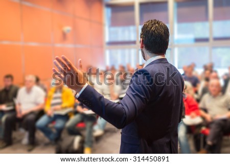 Speaker at Business Conference with Public Presentations. Audience at the conference hall. Entrepreneurship club. Rear view. Horizontal composition. Background blur.